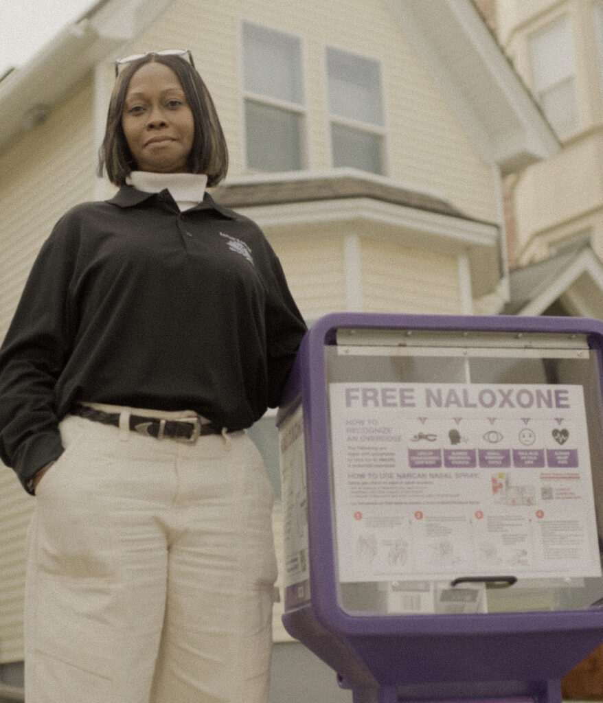 black woman standing next to a community naloxone dispenser